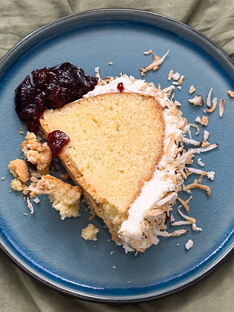 Image of slice of coconut cake, butter cream icing, cherry jam / homemade baking dessert on plate, soft layers, fluffy texture