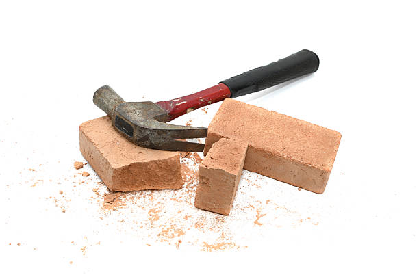 istock Shattered brick pieces and a hammer isolated on a white background 2221810302