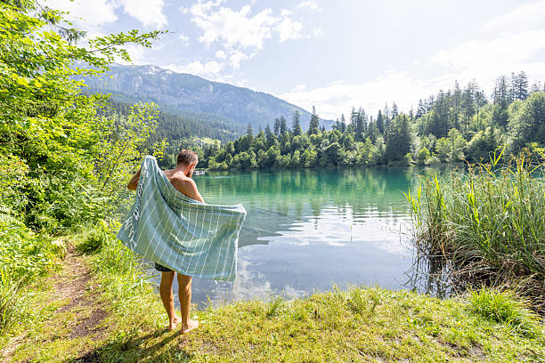 istock Man Drying off after Swim in Scenic Lake Surrounded by Forest 2221813185