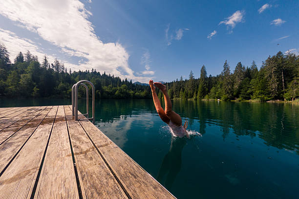 istock Person Performing Dive into Tranquil Lake from Wooden Dock 2221813269
