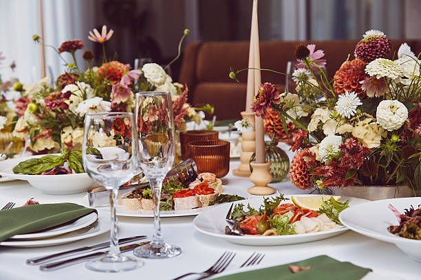 Aesthetic stylish autumn table setting, arranged flowers and candles under natural light. Cozy holidays table setup