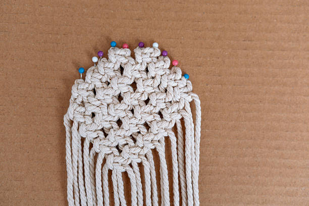 Round pinned macrame piece with colorful pins on cardboard background