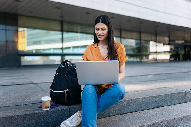 istock Young student working with laptop sitting on university stairs 2221824411