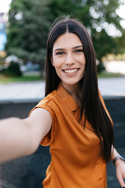 istock Young woman taking a selfie outdoors, smiling at the camera 2221825200