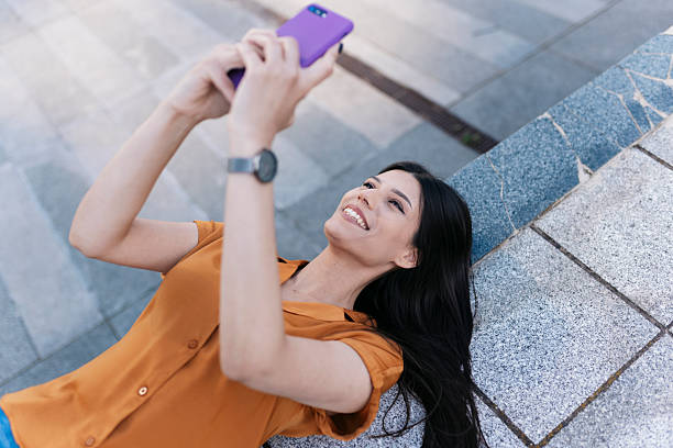 Young woman using mobile phone lying down outdoors