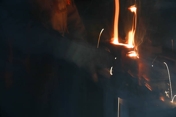 Welder in protective gear skillfully joining metal pieces, generating a dazzling display of sparks and smoke in a dimly lit workshop filled with industrial machinery