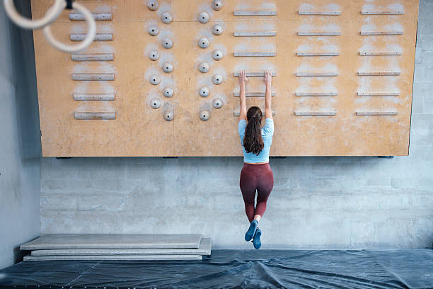 Sporty man dressed in rock climbing outfit training in bouldering gym