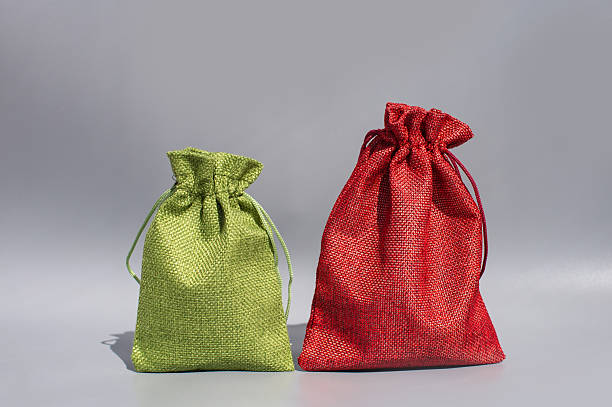 Green and red drawstring fabric pouches on gray background.