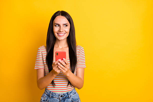 istock Photo portrait of young brunette using cellphone browsing internet looking empty space isolated on vivid yellow color background 2221830462