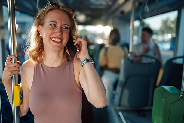 istock Cheerful young woman talking on smartphone while riding bus 2221831176
