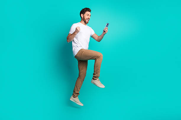 istock Excited young man celebrates success while holding a smartphone against a vibrant teal background 2221832407