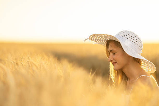 Young woman posing in a tall grassy field in the early evening.