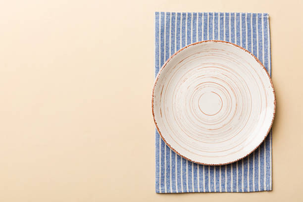 istock Top view on colored background empty round white plate on tablecloth for food. Empty dish on napkin with space for your design 2221834799