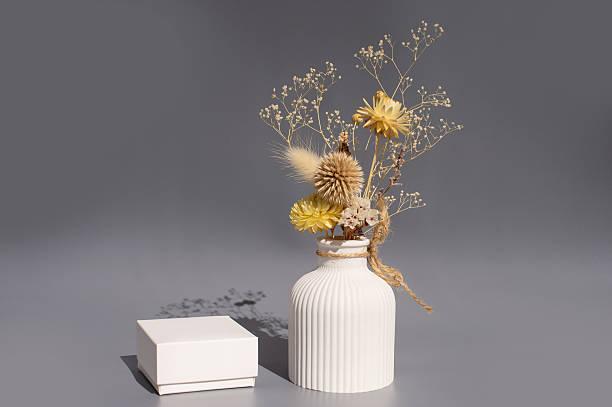 istock Dried floral arrangement in textured white vase with shadow on gray surface 2221835343