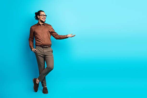 istock Young confident man gesturing with hand presentation on vibrant turquoise background, expressing relaxed and stylish demeanor 2221835528