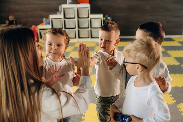 istock Lesson is over, high five. Children in kindergarten with their teacher 2221837355