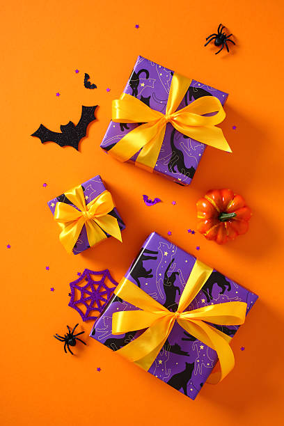 istock Halloween gift boxes and spooky decorations like spiders and bats on a vibrant orange background 2221840776