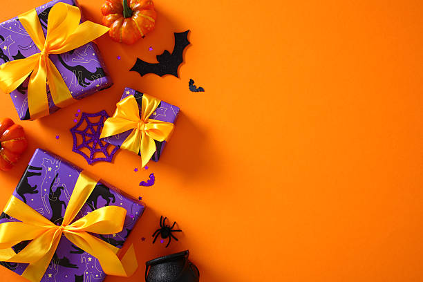 istock Halloween gift boxes with spooky decorations on orange background. Flat lay, top view, copy space 2221840815
