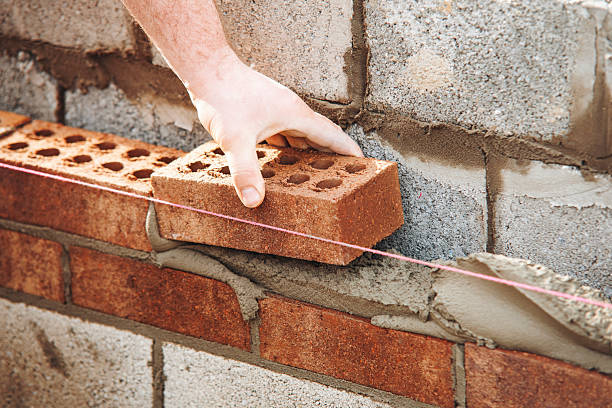 istock Close-up of skilled bricklayer working on construction site laying bricks for wall construction 2221841132