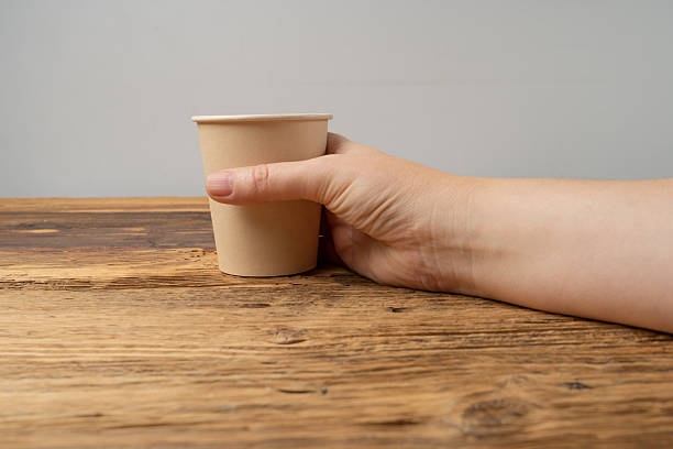 istock Hand Holds Cup, Empty Paper Cup in Hands, Coffee Mug, Teacup, Hot Beverage Mockup, Cup in Arms 2221841336