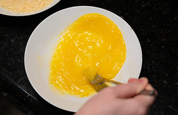 istock Female hands beat eggs with fork in a bowl, homemade schnitzel cooking process closeup 2221841584