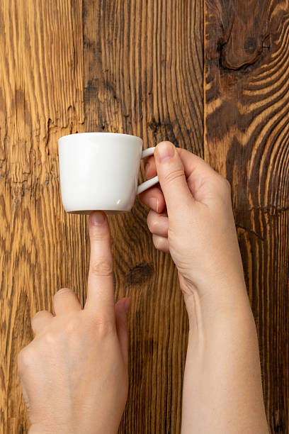 istock Hand Holds Cup, Empty White Cup in Hands, Coffee Mug, Teacup Mockup, Cup in Arms on Wooden Table 2221841630