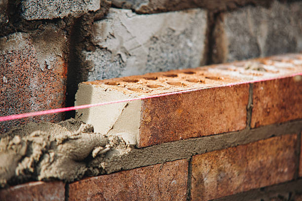 Close-up of skilled bricklayer working on construction site laying bricks for wall construction