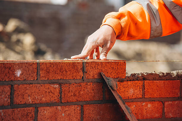 bricklayer laying another brick in the wall on construction site for sturdy wall - murare bildbanksfoton och bilder