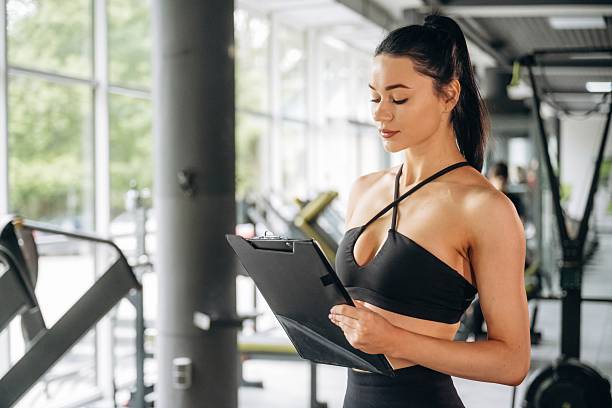 istock Female trainer is standing in the gym with notepad 2221853420