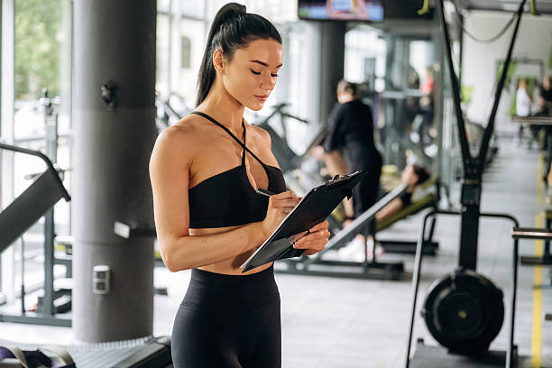 istock With notepad. Female trainer is standing in the gym 2221853431