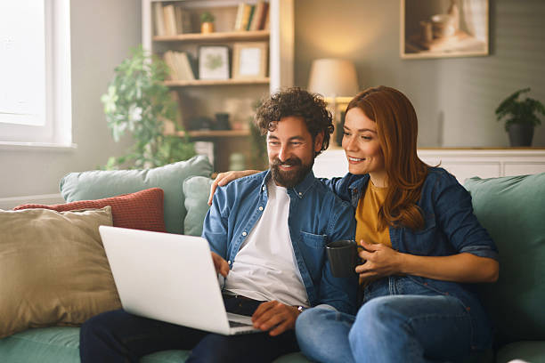 istock Happy couple relaxing on sofa browsing internet on laptop 2221854803