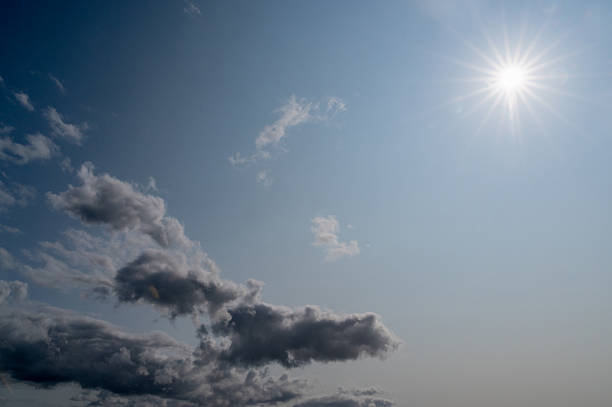 A beautifully serene sky showcases soft, fluffy clouds under a warm, bright sun radiating its gentle warmth