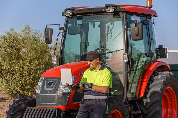 istock Farmer using laptop near red tractor in olive grove 2221858347