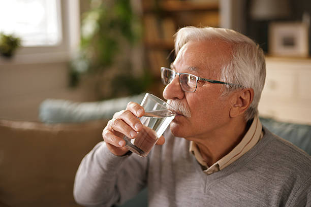 istock Senior man drinking water from glass at home 2221860002