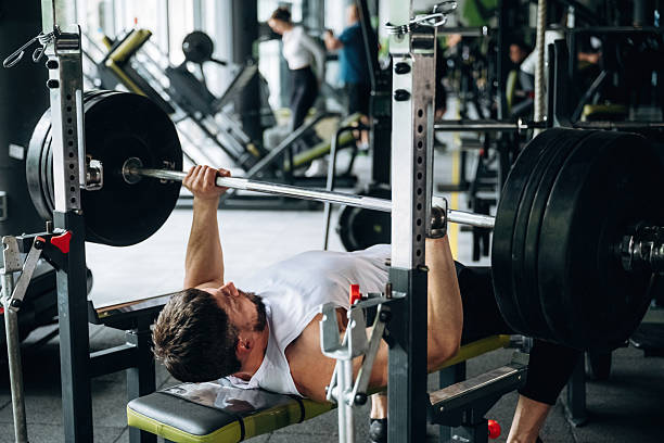 istock Lying down and pushing the barbell. Strong man is working out in the gym 2221863232