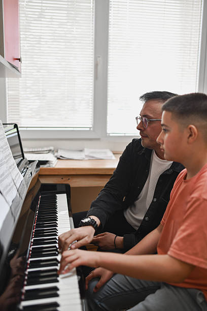 istock Music Instructor and Student Enjoying Piano Duet With Serious and Focused Faces 2221863674