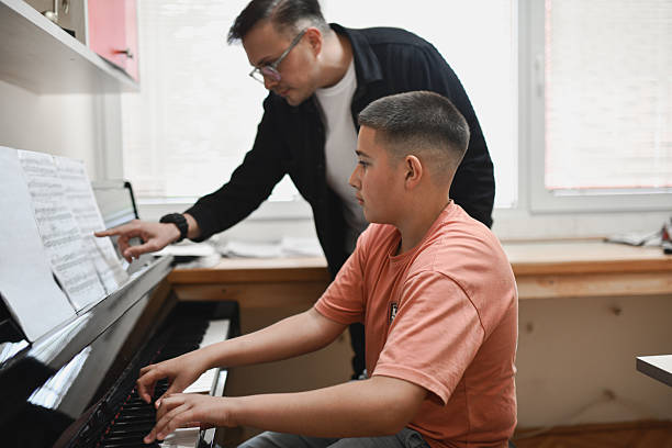 istock Instructor Pointing at Music Sheet While Student is Playing Piano With Full Concentration 2221863940