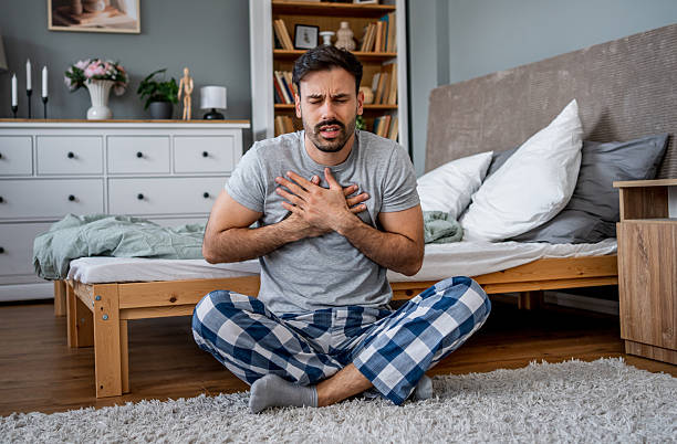 istock Man suffering chest pain while sitting on bedroom floor 2221864884