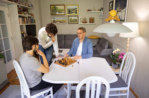 istock Dad Teaching Sons How to Play Chess Indoors 2221866529