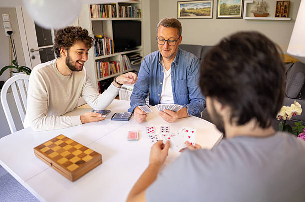 istock Two generations playing cards at home , chess on the table 2221866911