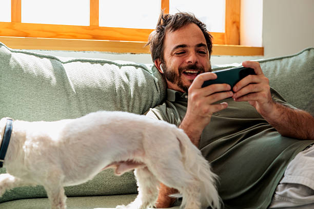 istock Man Playing Smartphone Game with Pet Dog on Couch 2221868541