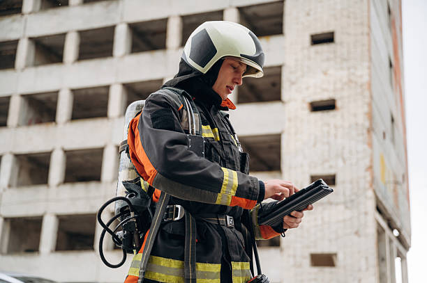 istock Tablet in hands. Professional firefighter is standing outdoors against big unfinished building 2221874324