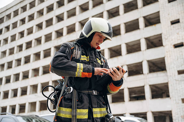 istock Tablet in hands. Professional firefighter is standing outdoors against big unfinished building 2221874341