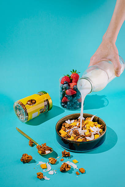 istock Pouring milk over cereal bowl with fresh fruit on bright backdrop 2221874461