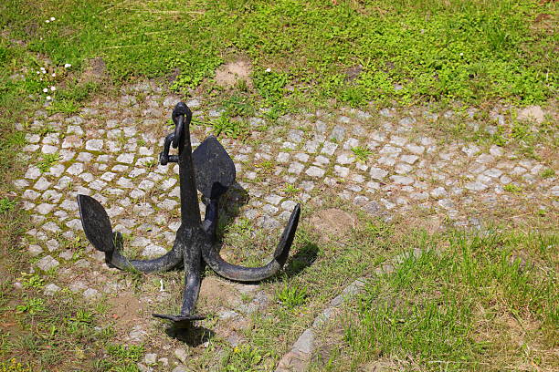 A heavy anchor displayed at the entrance to a coastal and maritime marina.