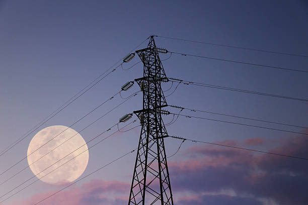 Electricity transmission tower silhouetted against blue sky at dusk