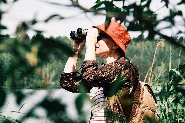 istock Forest lake in summer. Female hiker is watching birds using binoculars 2221879166