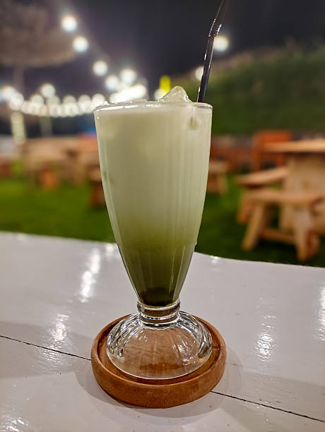 Creamy Matcha Iced Latte Served on Wooden Coaster at Outdoor Cafe