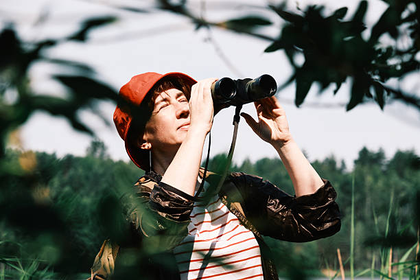 istock Summer forest. Female hiker is watching birds using binoculars 2221879468