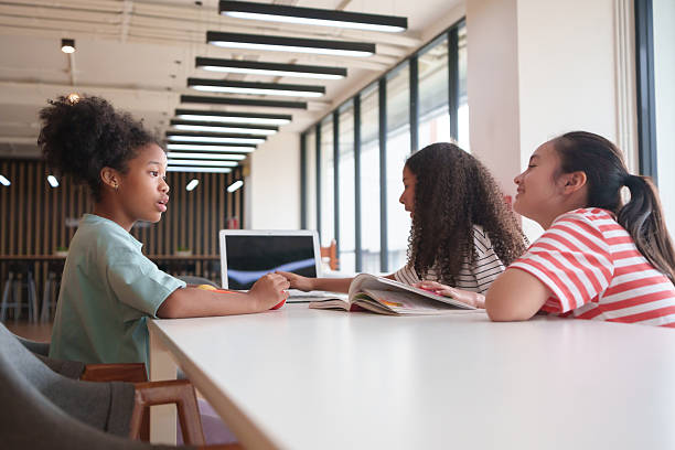 istock Three diverse little girls sitting together at a white table in a modern classroom with a laptop, multiethnic children studying. 2221881321